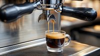 Fresh espresso with golden crema pouring from professional coffee machine into glass cup, close-up shot showing rich layers and brewing process.