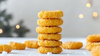 Golden cornmeal cookies stacked in tower against blurred bokeh background. Fresh baked traditional homemade treats with crispy texture and warm glow lighting.