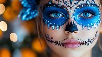 Woman wearing sugar skull makeup with bright blue eyeshadow, rhinestones, and intricate black face paint design against blurred bokeh lights background for Halloween or Day of Dead.