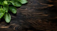 Fresh green basil leaves on dark rustic wooden background with natural wood grain texture and copy space for menu or recipe design.