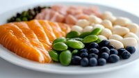 Fresh salmon fillet with edamame beans, blueberries, white beans and seaweed on plate. Healthy protein-rich meal for balanced nutrition and wellness.