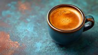 Fresh espresso with golden crema in dark ceramic cup on textured turquoise background with copper highlights. Minimalist coffee composition with copy space.