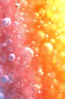 Dreamy soap bubbles floating on pink and orange gradient background with soft bokeh lights and sparkles creating magical atmospheric effect.