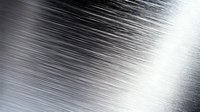 Brushed metal surface with diagonal lines creating dynamic light reflection pattern. Industrial steel texture background with polished metallic finish.