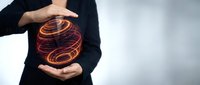 Business professional holding glowing orange energy sphere with swirling light trails between hands representing innovation, technology solutions and creative power.