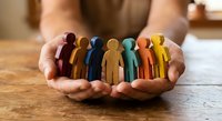 Hands holding colorful wooden human figures representing diversity, teamwork and inclusion concepts for business presentations and social campaigns.
