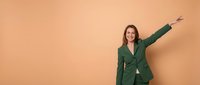 Happy businesswoman in green suit celebrating success with raised arms against orange background for corporate presentations.