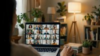 Diverse group of people participating in online video conference meeting on laptop screen in modern home office with plants and warm lighting.