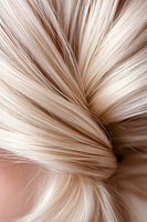 Close-up macro shot of blonde hair strands showing texture and shine with soft beige tones and natural movement in detailed view for beauty and haircare concepts.