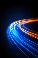 Dynamic curved light trails in blue and orange glowing against dark background create futuristic motion effect, suggesting speed and technology advancement.