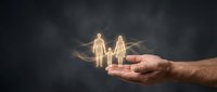 Glowing family figures floating above protective cupped hands against dark background symbolizing care, insurance coverage and family protection concept.