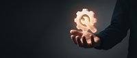 Businessman hand holding glowing gear icon symbolizing innovation, technology solutions, and industrial process optimization for business growth.