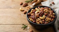 Mixed nuts assortment with walnuts, pecans, cashews and almonds in rustic bowl on wooden background for healthy snacking and cooking ingredients.