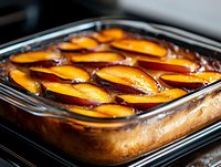 Caramelized apple slices arranged on golden sponge cake in glass baking dish, ready for serving or dessert photography.