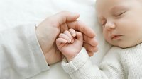 Newborn baby sleeping peacefully while holding adult hand in tender moment of connection and love on soft white blanket background for family concepts.
