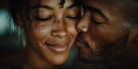Intimate moment of young African American couple sharing tender kiss, woman smiling with closed eyes, romantic relationship love connection in warm lighting.