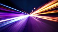 Abstract light trails on dark background with motion blur effect creating dynamic perspective view of speed and movement through time and space.