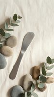Spa wellness flat lay with eucalyptus leaves, smooth river stones and gua sha tool on natural linen fabric for skincare and massage therapy treatments.
