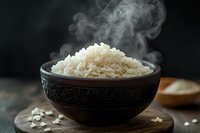 Steaming hot white rice served in traditional carved clay bowl on wooden board, with rising vapor and scattered grains creating atmospheric food composition.