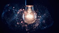 Glowing light bulb surrounded by sparkling particles and bokeh effects on dark blue background symbolizing innovation, creativity and bright ideas.