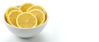 Fresh lemon slices arranged in white ceramic bowl on clean background for culinary and healthy lifestyle concepts.