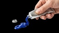 Hand squeezing blue paint from a silver tube, isolated on transparent background, ready for art, craft, sticker, t-shirt design, and print on demand use.