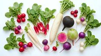 Fresh organic radishes and turnips with green leaves arranged on white background for healthy cooking and farm-to-table cuisine concepts.