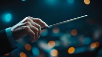 Orchestra conductor hands holding baton against blurred concert hall lights in turquoise and amber tones, dramatic musical performance atmosphere.
