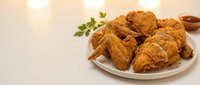 Crispy fried chicken pieces served on white plate with fresh parsley garnish and sauce, ready for food photography, restaurant menus, and culinary content.