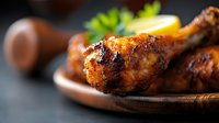 Grilled chicken drumsticks with crispy golden-brown skin and charred marks served on rustic wooden plate, garnished with fresh herbs and citrus slice.