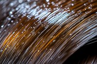 Close-up of brown hair strands with water droplets and light reflections, showing texture and moisture for haircare, beauty, and wellness concepts.