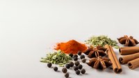Aromatic spices and herbs collection with cinnamon sticks, star anise, paprika powder, dried oregano and black peppercorns for culinary cooking.