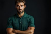 Confident bearded man in green polo shirt with crossed arms against dark background for business and lifestyle marketing campaigns.