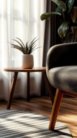 Modern beige armchair with wooden legs next to side table and air plant in contemporary living room with natural sunlight streaming through curtains.