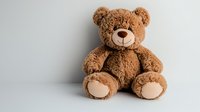 Fluffy brown teddy bear sitting against light background, soft plush toy with beige paws and nose, childhood companion for nursery decor and gift giving.