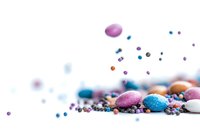 Colorful sugar sprinkles and dragees scattered on white surface with selective focus. Pink, blue and white candy decorations create festive baking composition.