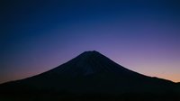 Silhouette of a majestic volcanic mountain peak against a dramatic twilight sky with purple and orange hues, suitable for travel and nature backgrounds.