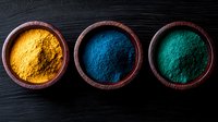 Vibrant yellow, blue and turquoise powder pigments in rustic wooden bowls arranged in row on dark wooden background. Natural color dyes for art and textiles.
