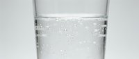 Clear sparkling water with bubbles in transparent glass against white background for health and hydration concepts.
