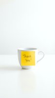 White ceramic coffee mug with a yellow sticky note saying Thank You on a clean white background, expressing gratitude and appreciation.
