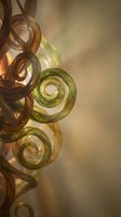 Abstract glass spirals in warm golden and green tones with soft lighting and shadows creating elegant decorative art composition for luxury interior design.