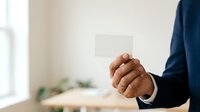 Man in business suit holding blank white card for corporate messaging and branding purposes.