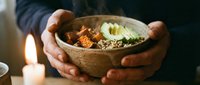 Hands holding wooden bowl with nourishing soup, garnished with herbs and seeds, wellness and healthy eating concept for nutrition and lifestyle content.