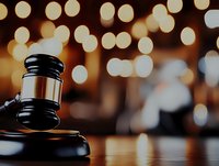 Wooden judge gavel on sound block against warm bokeh lights background, symbolizing justice, law enforcement and court decisions in dramatic lighting.