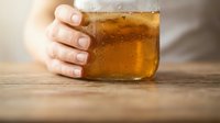 Person holding glass of beer on wooden table, suitable for beverage, lifestyle, and hospitality design projects.