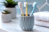 Colorful toothbrushes in geometric ceramic holder on bathroom counter with white towel and plants, modern minimalist dental hygiene setup for family.
