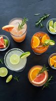 Refreshing citrus cocktails with rosemary garnish on dark slate background for summer entertaining and mixology concepts.