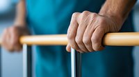 Close-up of elderly African American hands gripping walking support rails during physical therapy rehabilitation session, showing determination and recovery progress.