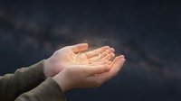Cupped hands holding warm glowing light against dark cloudy sky background symbolizing hope, protection, spirituality and divine energy concept.