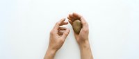 Hands gently cupping and protecting wooden heart shape on white background. Concept of care, love, protection and emotional support in relationships.
